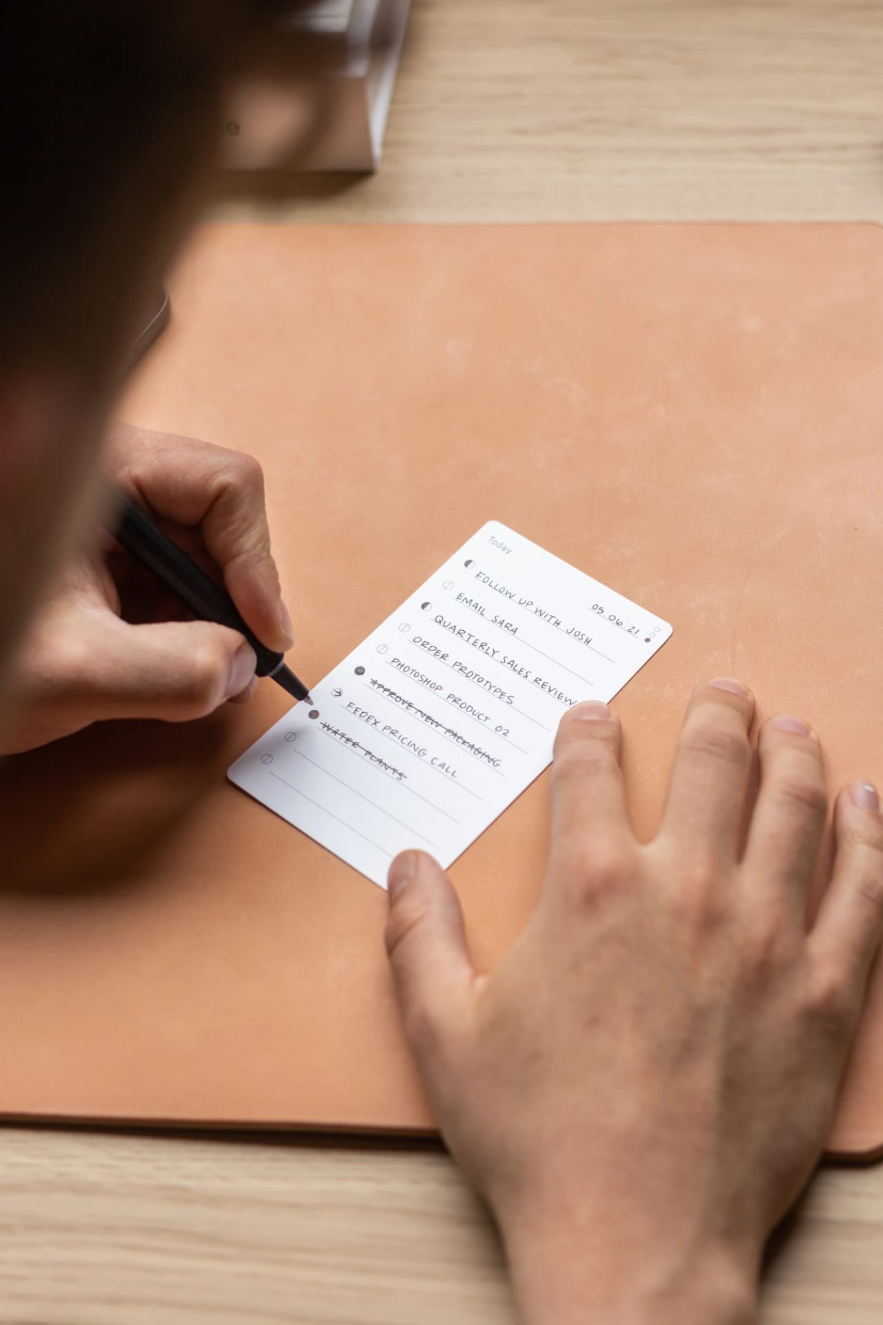 Person using a pen to cross a task off a productivity paper card.