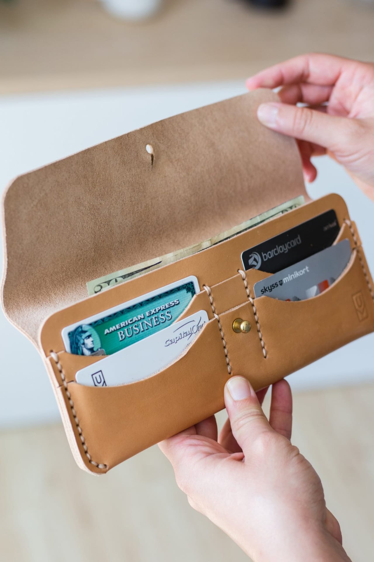 Leather long wallet held open with hand-stitched card dividers, full-length bill pocket, and simple tab closure.