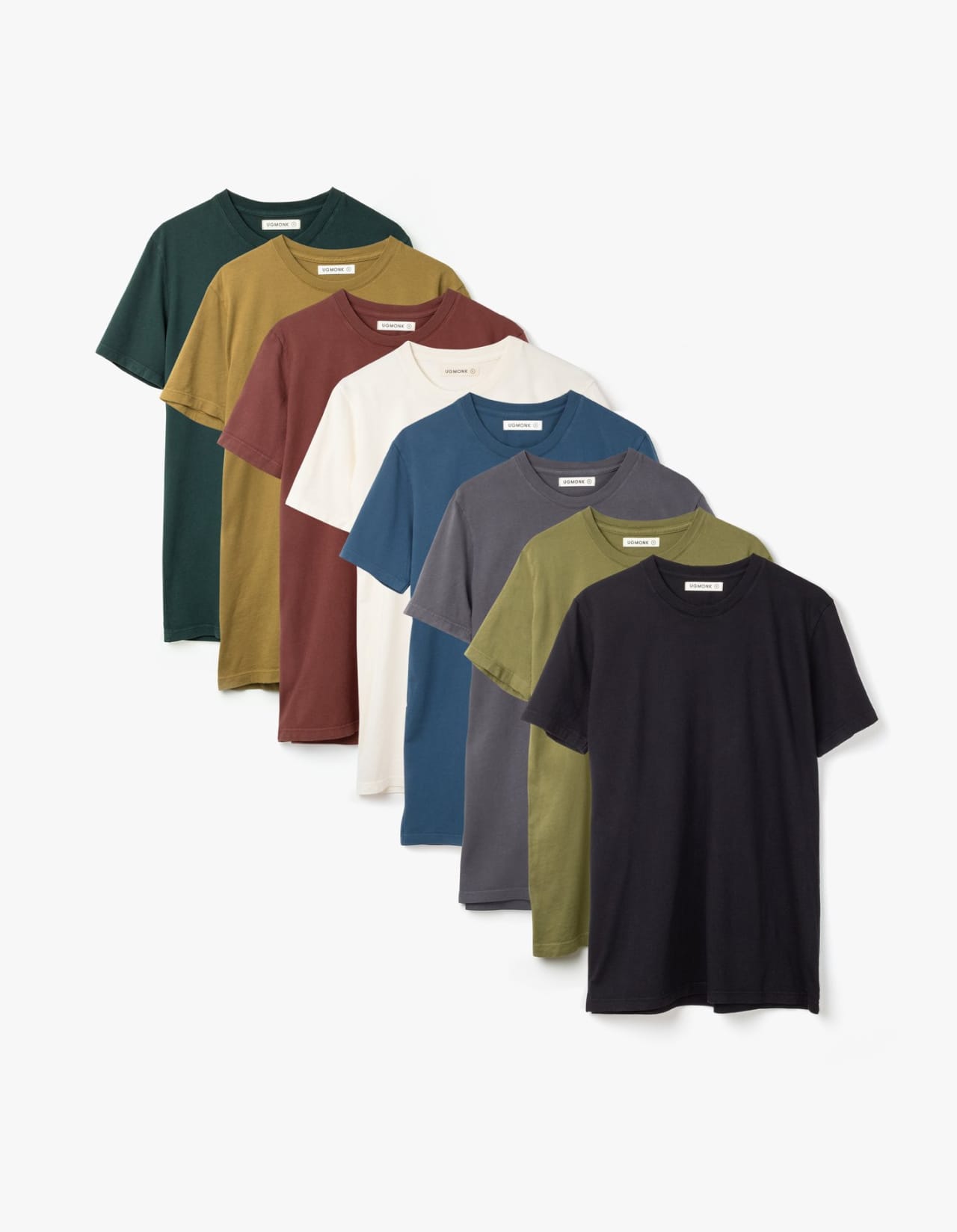 Eight shirts arranged on table in black, olive, grey, blue, white, red, mustard, and green.