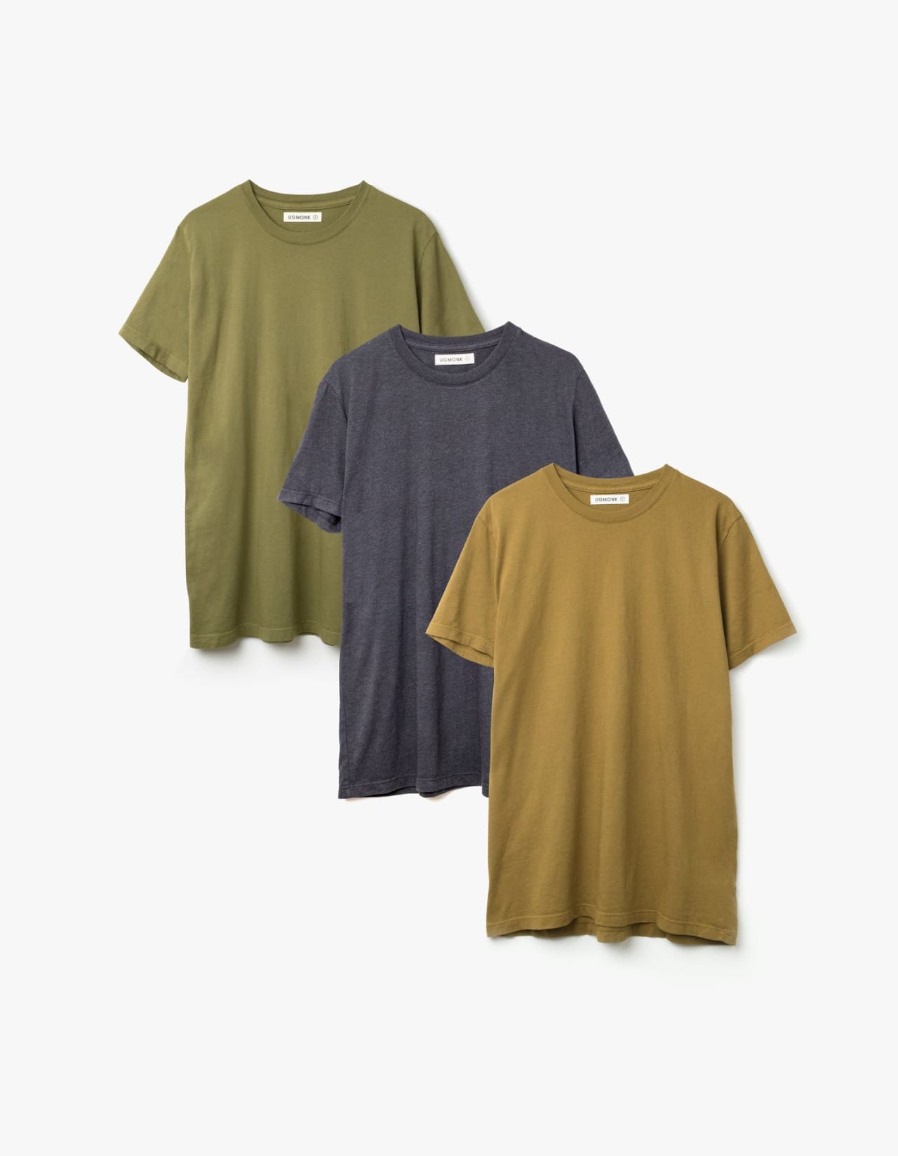 Three shirts arranged on table in mustard, dark gray, and olive.