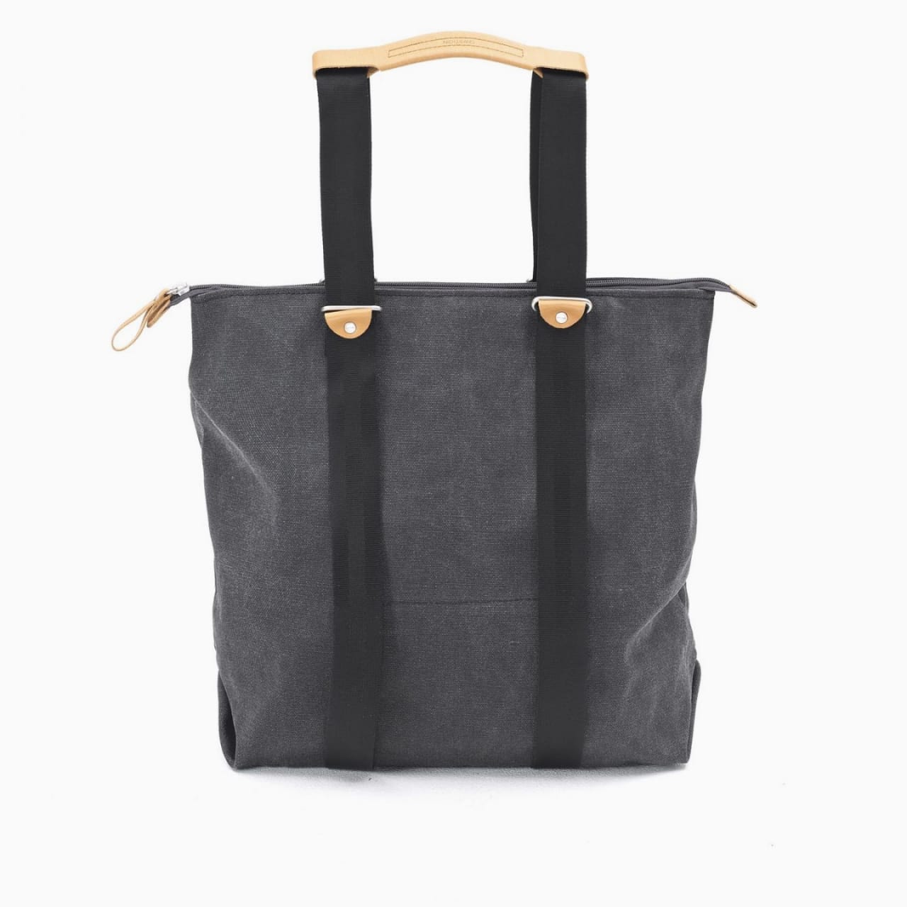 Front of tote bag with washed black canvas body, black straps, and tan leather handles and accents.