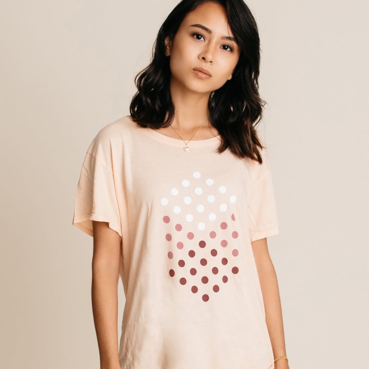 Model wearing women's artwork tee with isometric dots forming a cube in small.