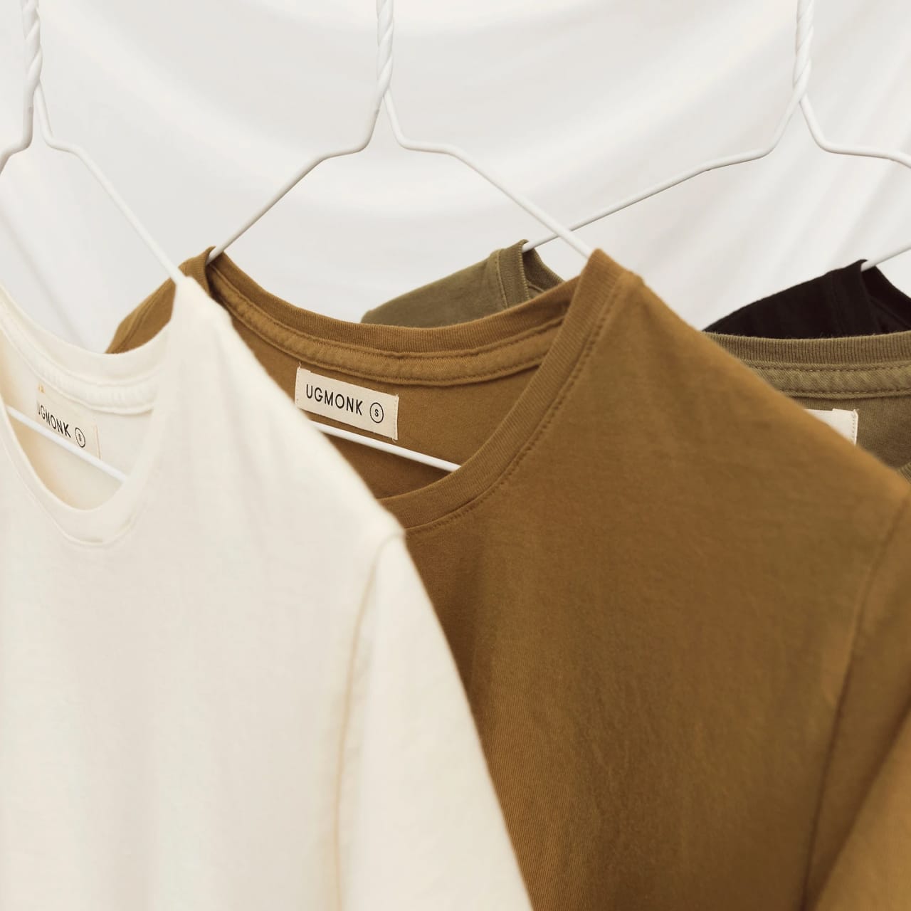 Close up of Basic Tee fall bundle with off-white, ochre, olive, and black tees.