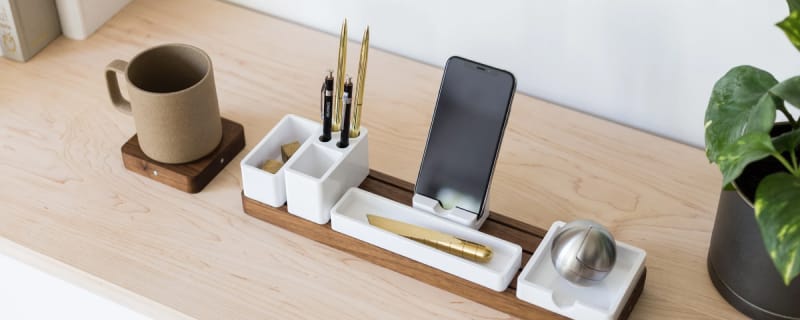 Walnut organizer base with pen, sticky note, phone, and bin trays, next to modular drink coaster attachment.