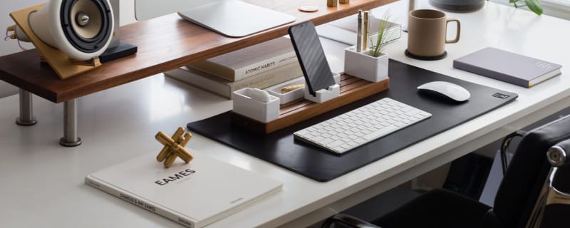 Walnut organizer system on black leather desk mat on top of white desk.