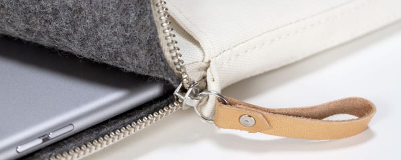 Detail of zipper pull with tan leather and silver rivet.