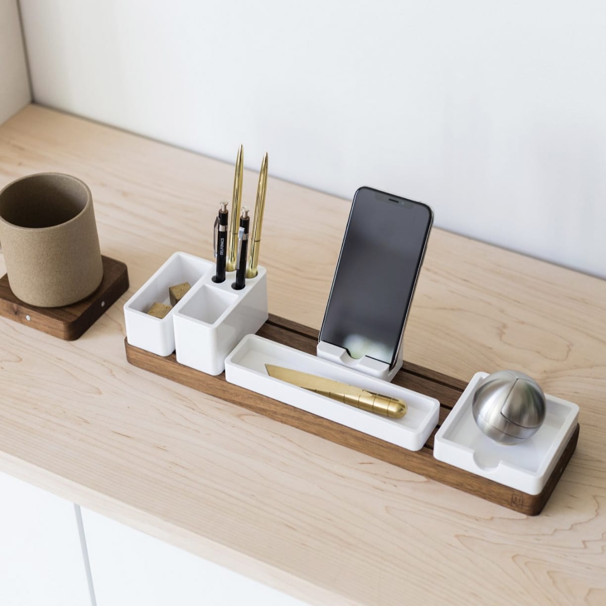 Walnut desk organizer set with white modular trays, next to porcelain mug on wooden desk.