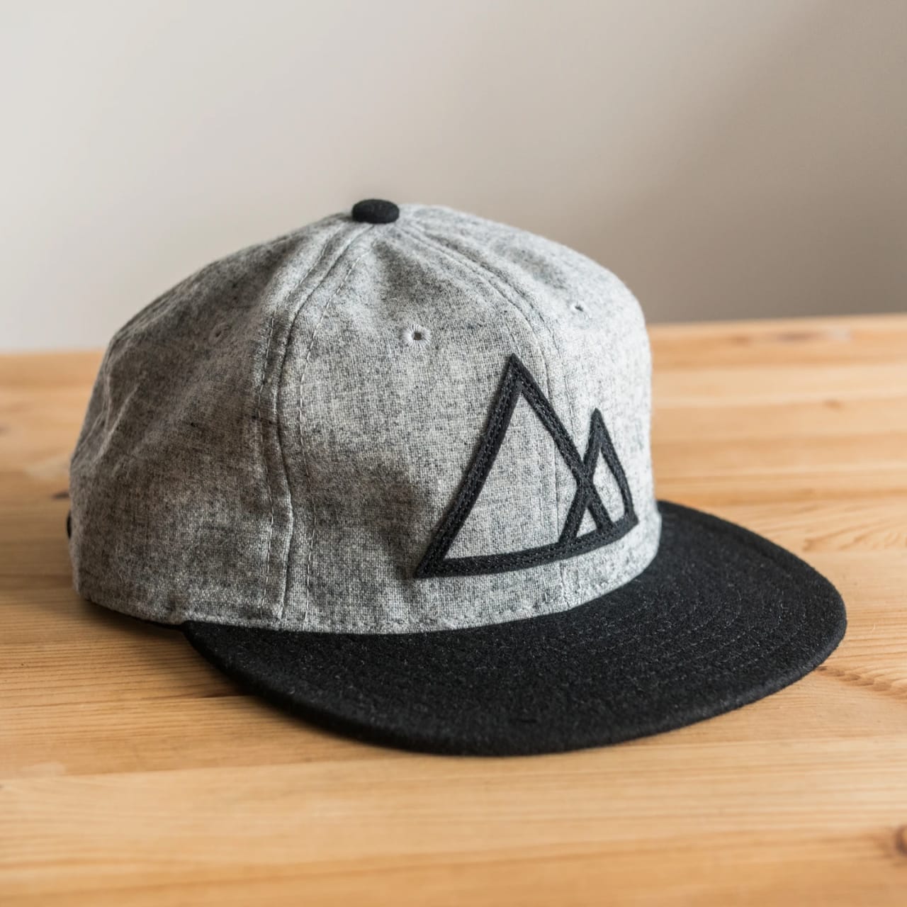 Grey 6-panel baseball hat with black brim, black mountain graphic on front, and light heather gray body.