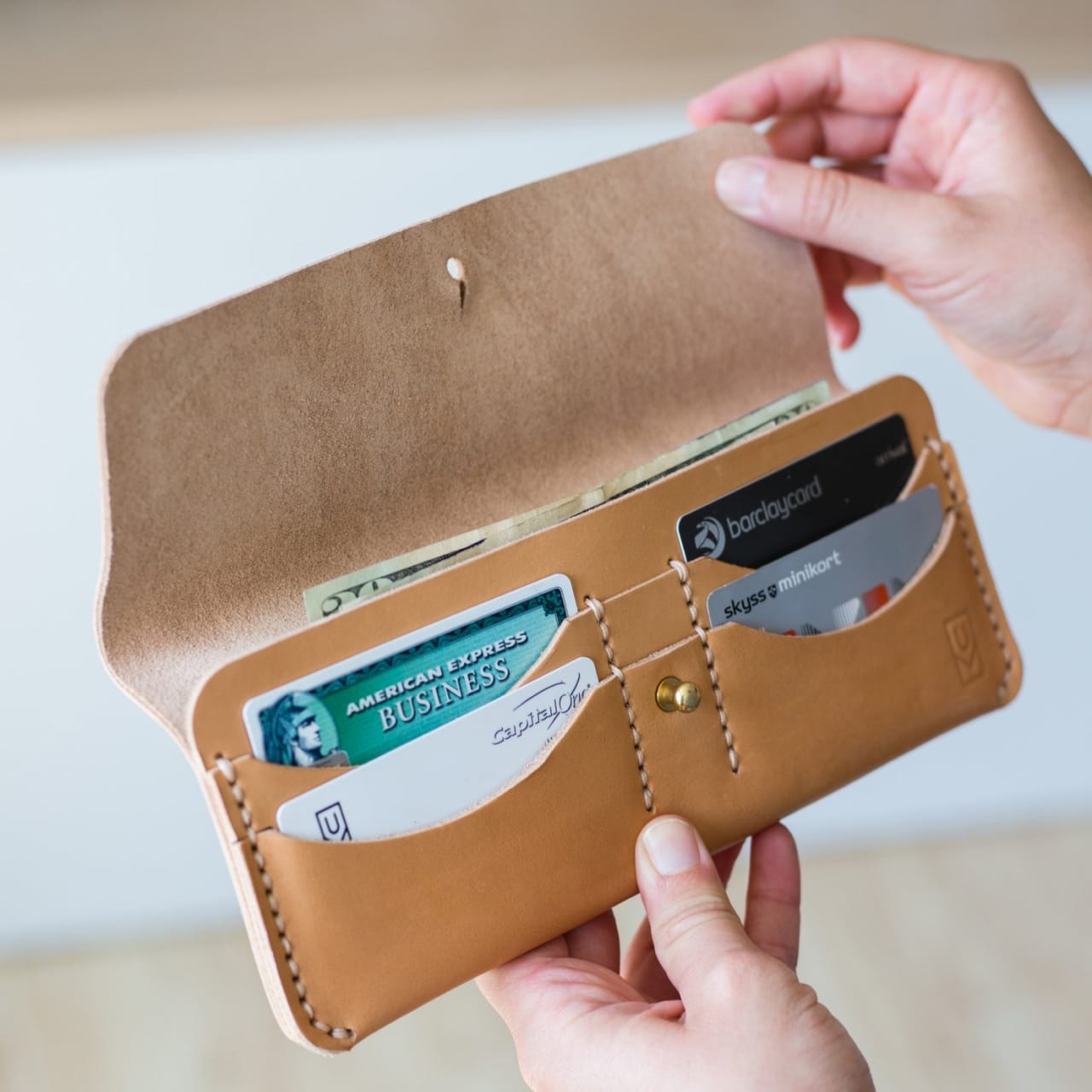 Model opening tan leather long wallet with credit card pockets and cash pouch.